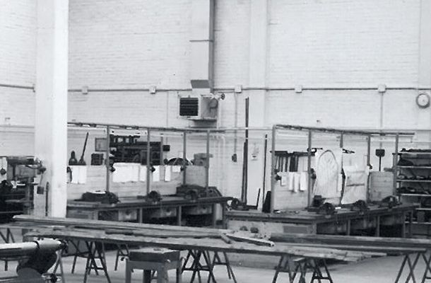 schwarz-weiße fotografie einer arbeitshalle mit Tischplatten aus Holz