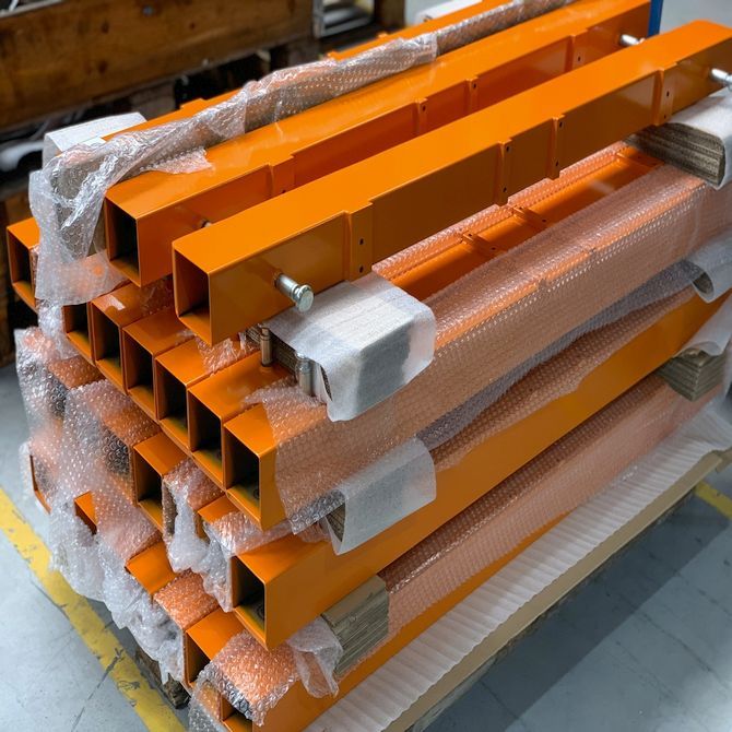 pulverbeschichtete metallteile in orange auf einer palette