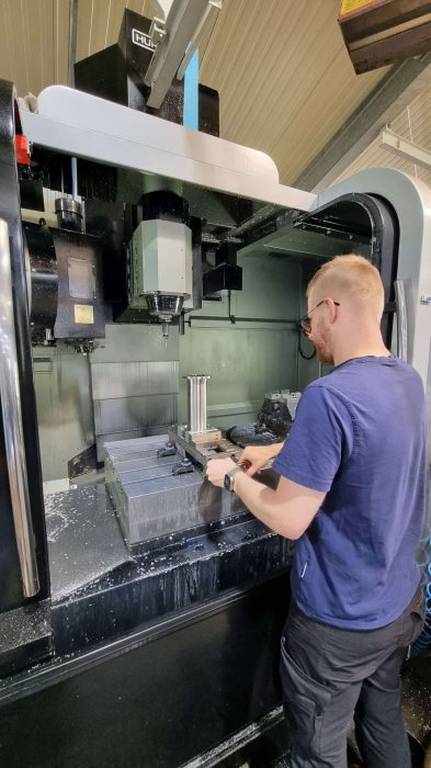 mitarbeiter wechselt das werkzeug an der fräsmaschine
